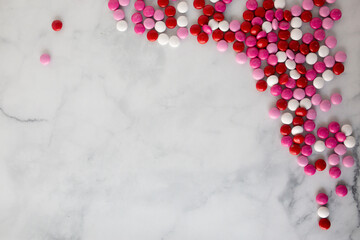 flat lay of red, white, and pink chocolate candies spilled onto a marble countertop