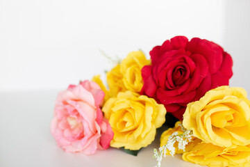 pink, red and yellow roses flat lay against a white background