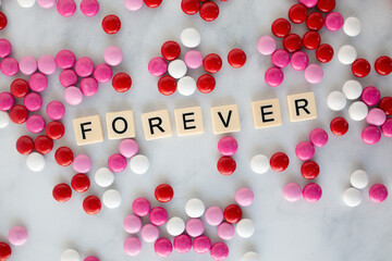 the word forever written in scrabble tiles on a marble kitchen counter top surrounded by valentines candy