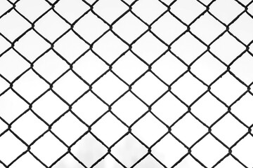 Black metal wire fence with rhombuses in park, view on white sky through it, camera in motion. Background, texture with metal grid and overcast sky in autumn day.