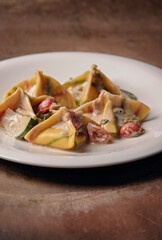 Italian dish.Ravioli with sauce, tomates cherry and zucchini on the plate..