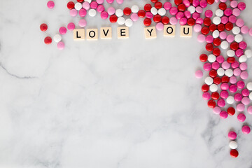 the words love you written in scrabble tiles on a marble kitchen counter top surrounded by valentines candy