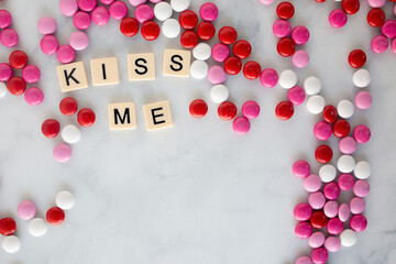 the words kiss me written in scrabble tiles on a marble kitchen counter top surrounded by valentines candy