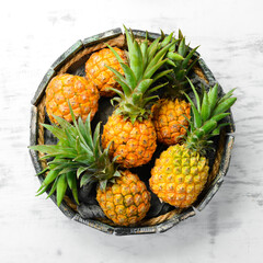 Pineapples in a wooden box. Ripe baby pineapple. Tropical fruits. Top view. Free space for text.