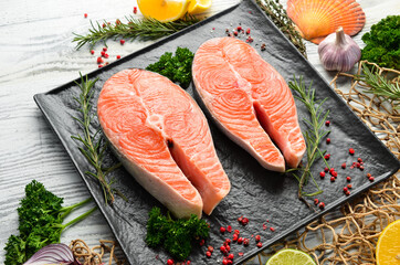 Raw salmon steak with spices. On a white wooden background. Top view.