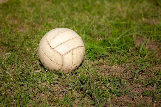 great photo. summer time. sunlight. old gray volleyball ball on green grass. soccer ball. yard sports. village entertainment.