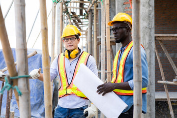 Professional Construction and  Engineer team Working on workplace. Professional black architect and construction worker working look at blueprint plan on site.