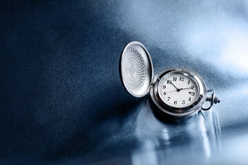 Pocket watch on a rough metal surface with copy space.