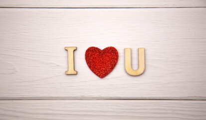 The word i love you made from decorative wooden letters on a light wooden background with glitter red hearts. Valentine's day poster, greeting card, banner