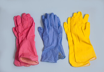 Three pairs of multi-colored rubber gloves lie on a blue background. Cleanliness concept.