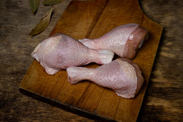 Raw chicken legs on a wooden board. Chicken legs on an old wooden surface. Chicken meat.