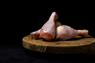 Raw chicken legs on a wooden board. Chicken legs on a black background. Chicken meat.
