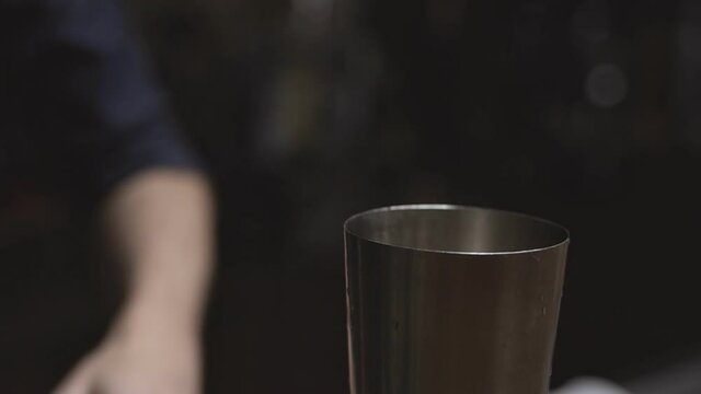 Bartender with shovel pouring ice into glass jug and preparing cocktail at bar counter - alcohol drinks, people and luxury concept