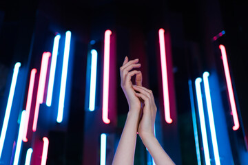 Hands of a dancing young woman close-up. Hip hop dancing against neon lamps