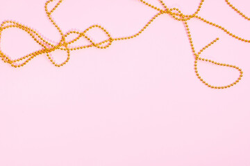 Valentine's Day or birthday concept. Golden beads on a pink background. Top view.
