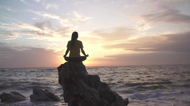 Yoga woman in Lotus position practicing yoga and meditation. outdoors on the evening ocean