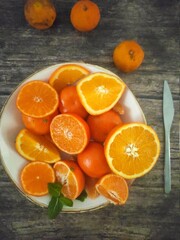 A white plate full of orange slices and tangerines 