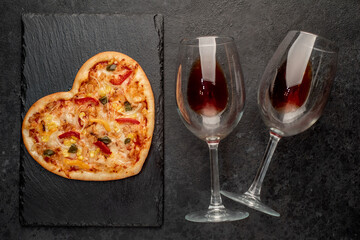 dinner for two on saint's day
 valentine. heart shaped pizza and red wine on stone background
