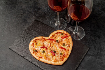 dinner for two on saint's day
 valentine. heart shaped pizza and red wine on stone background