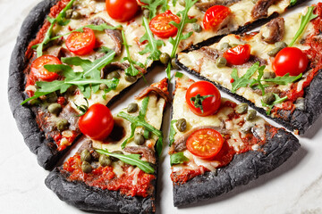 black dough pizza with anchovy arugula, capers