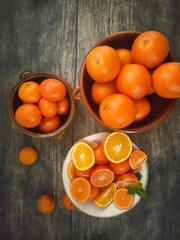 Mixed citrus fruits in bowls on a dark wooden table: oranges, mandarin oranges and tangerines