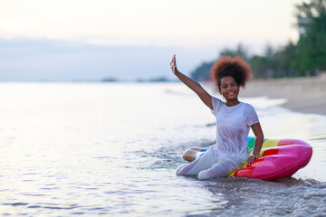 African girl playing on the beach with pink inflatable tube