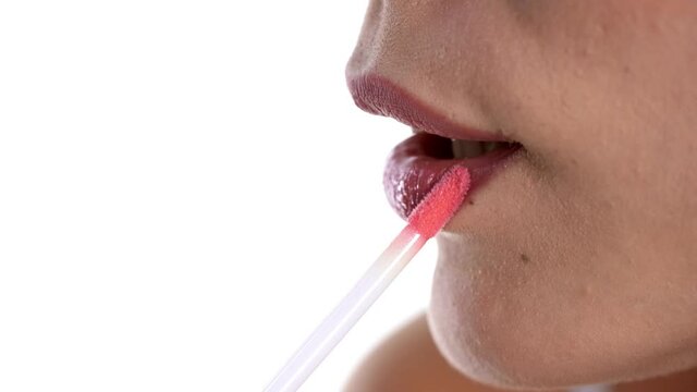 Closeup of woman applying a lip gloss on her lips
