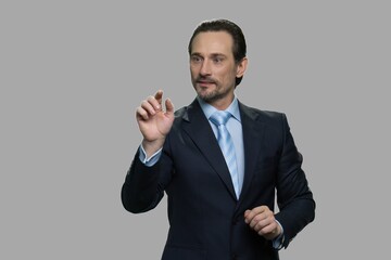 Businessman in suit working with invisible interface. Man working with virtual screen on gray background. People, business, modern technology concept.
