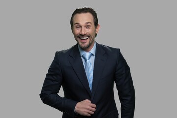 Portrait of laughing businessman on gray background. Overjoyed businessman is laughing hard at something hilarious.