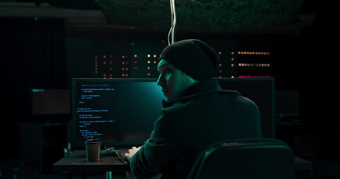 A young hacker is arrested, puts his hands up, surrenders as he enters data into an online computer system and distributes stolen personal data around the world.