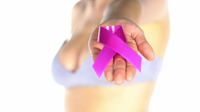 a woman in a bra holds in her hand a pink ribbon on a white background