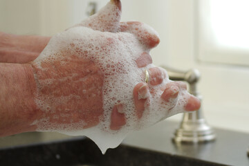 Fototapeta premium Washing hands with soap and foam in a kitchen sink, hygiene to prevent corona virus to spread