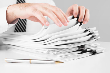 Businessman hands working in stacks of paper files for searching information, business and...