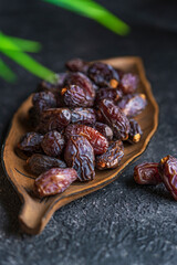 Selective focus or dried dates organic fruits on a plate plate, black textured table with copy space.