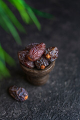 Selective focus or dried dates organic fruits on a plate plate, black textured table with copy space.