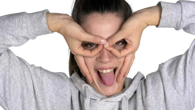 a young woman making funny faces and glasses with her fingers on white background