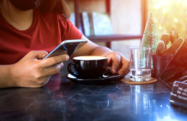 Young woman sitting in coffee shop at table,Female holding phone and looking on his screen in coffee shop. drinking coffee and using smartphone working with a tablet,The concept of the business idea.
