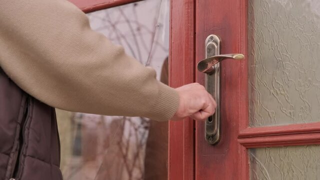 a man opening the security door of the house by turning a key in the lock.