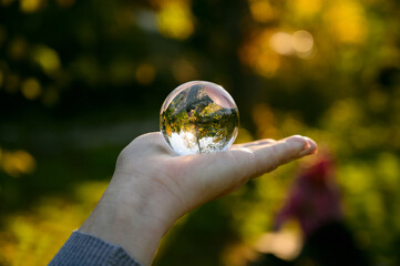 Hand held lensball in autumn forest. Selective focus with shallow depth of field.