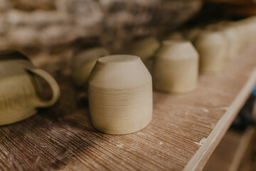 Wet handmade clay mugs on the shelf