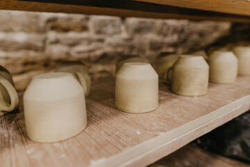 Wet handmade clay mugs on the shelf
