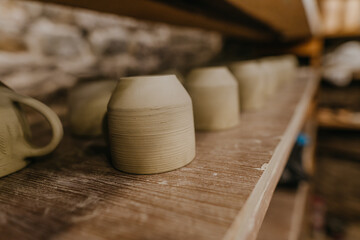 Wet handmade clay mugs on the shelf