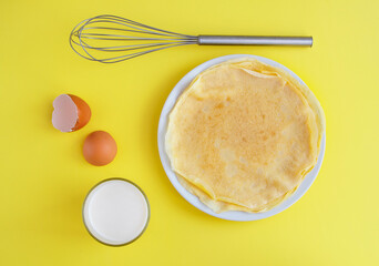 Flat composition with thin pancakes on bright yellow background