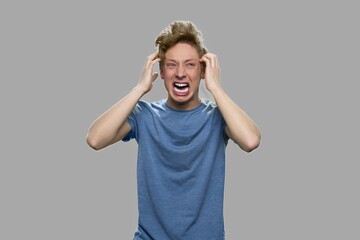 Stressed angry teenage boy. Emotional portrait of furious teenager screaming with anger against...