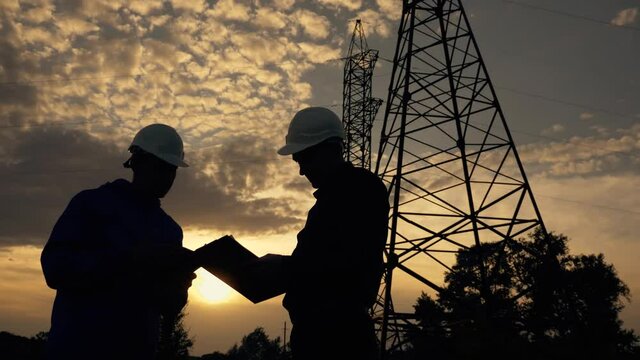 Electric energy concept, technology. engineer works with energy project.Industrial technology worker man working on project concept. Silhouette man engineer working with high voltage electricity pylon