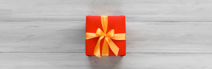 red box tied with a gold ribbon. the ribbon is tied on a box in the form of a beautiful bow. holiday gift concept