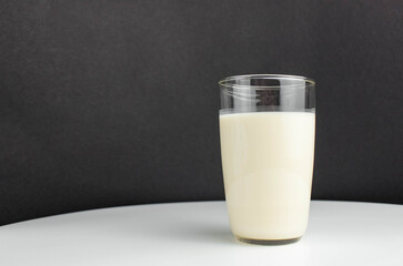 Milk in a clear glass on a black and white background.