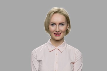 Happy face of pretty blonde woman. Beautiful smiling business woman looking at camera on gray...