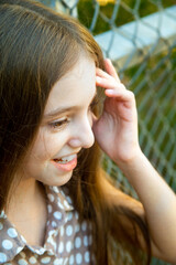 a girl stands near the net and straightens her hair with her hand