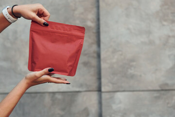Close up view of woman's hands that holds red package of new coffee